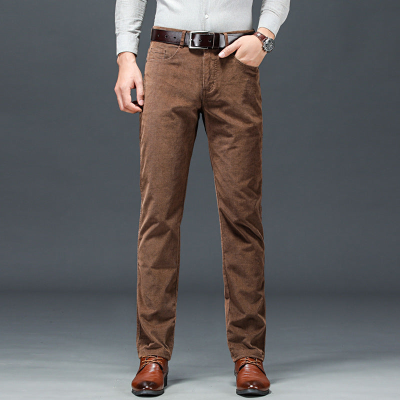 Uomo in camicia bianca e pantaloni marroni eleganti, cintura in pelle, scarpe in cuoio, posa su sfondo grigio. Moda maschile casual chic.