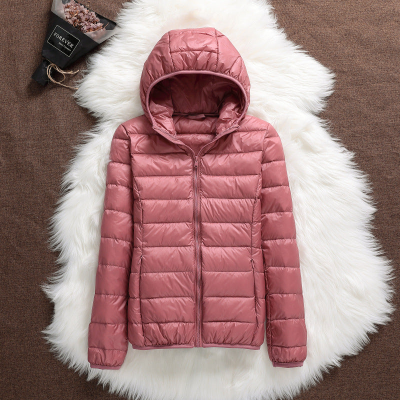 Giacca invernale rosa con cappuccio, imbottita e trapuntata, su sfondo di pelliccia bianca. Moda donna, abbigliamento caldo, stile casual.