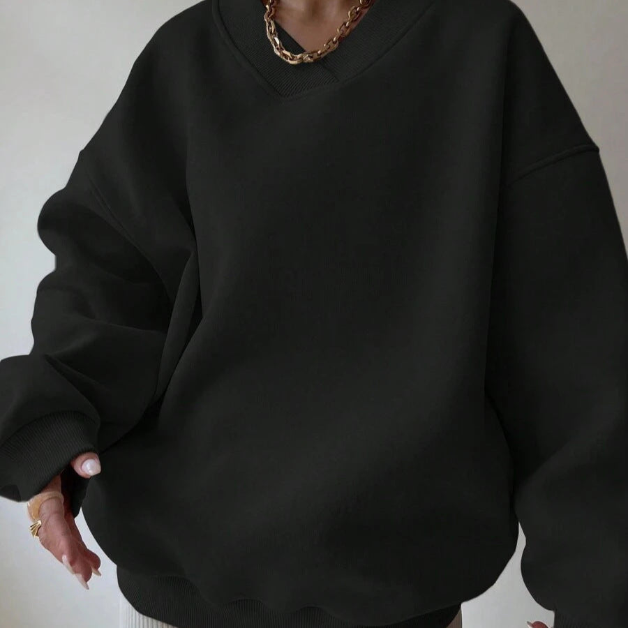 Maglione oversize nero, stile casual, indossato con collana a catena dorata. Moda autunnale, abbigliamento comodo, tendenze streetwear.