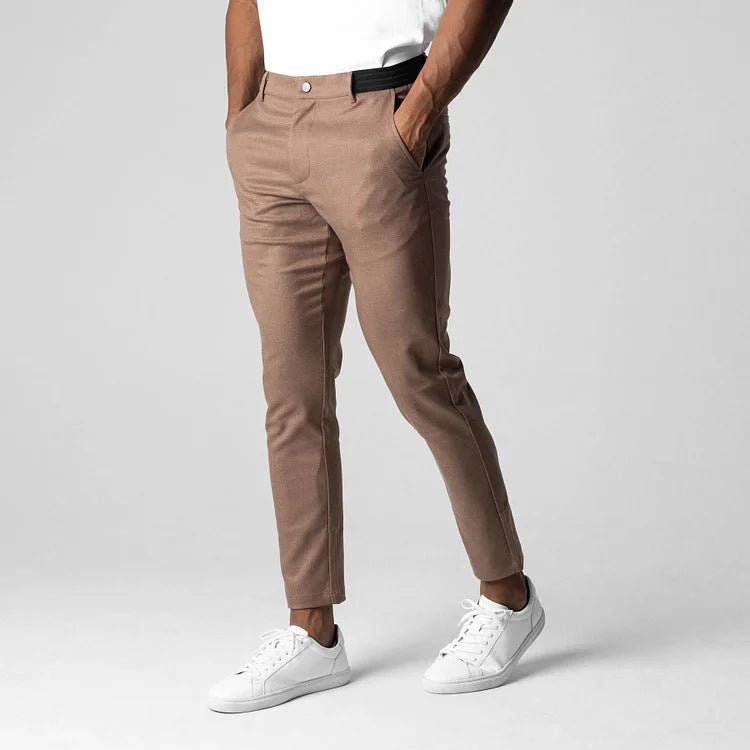 Pantaloni chino beige da uomo, eleganti e moderni, abbinati a scarpe da ginnastica bianche. Stile casual, moda maschile, abbigliamento trendy.