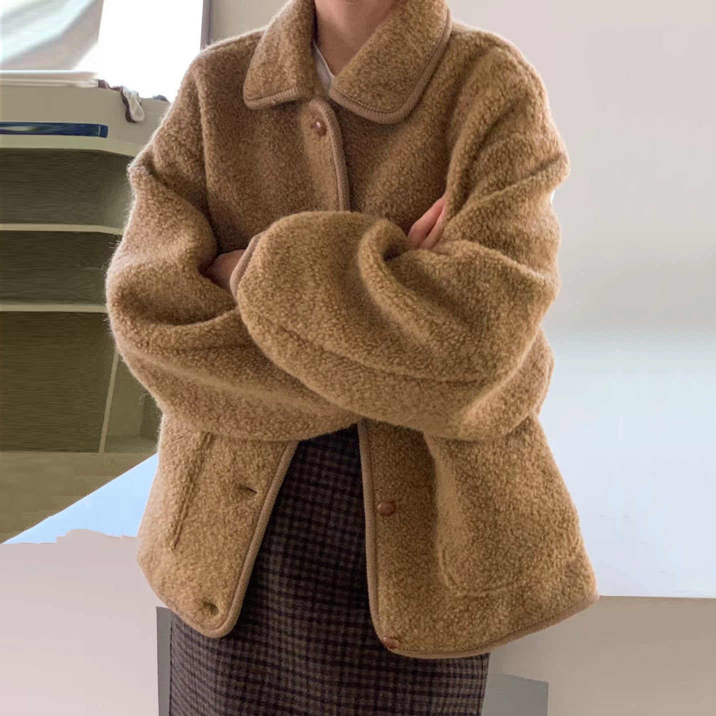 Giacca in pile teddy beige, oversize, con bottoni, indossata su gonna a quadri. Moda autunnale, abbigliamento casual, stile caldo e accogliente.