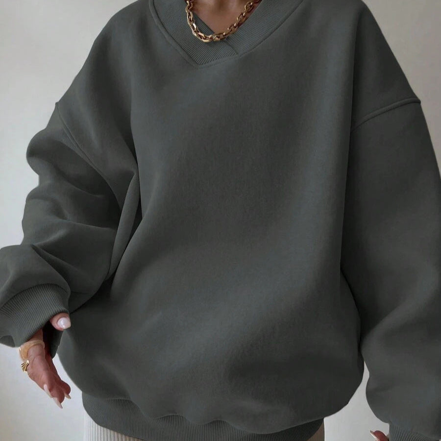Donna con felpa oversize grigia, collana dorata, stile casual chic. Moda autunnale, abbigliamento comodo, tendenze streetwear.