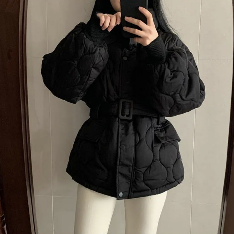 Donna con giacca nera imbottita e cintura, scatta selfie allo specchio. Moda invernale, abbigliamento caldo, stile casual chic.