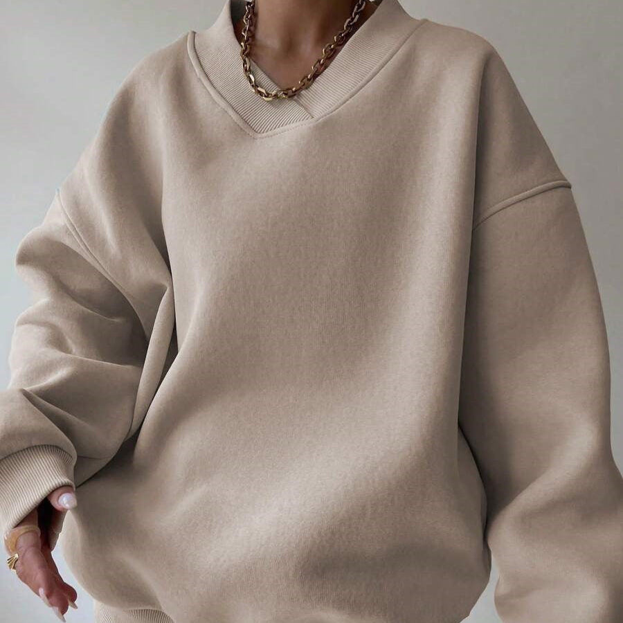 Maglione oversize beige su persona, con collana a catena dorata. Moda casual autunno, stile minimalista, tessuto morbido e confortevole.
