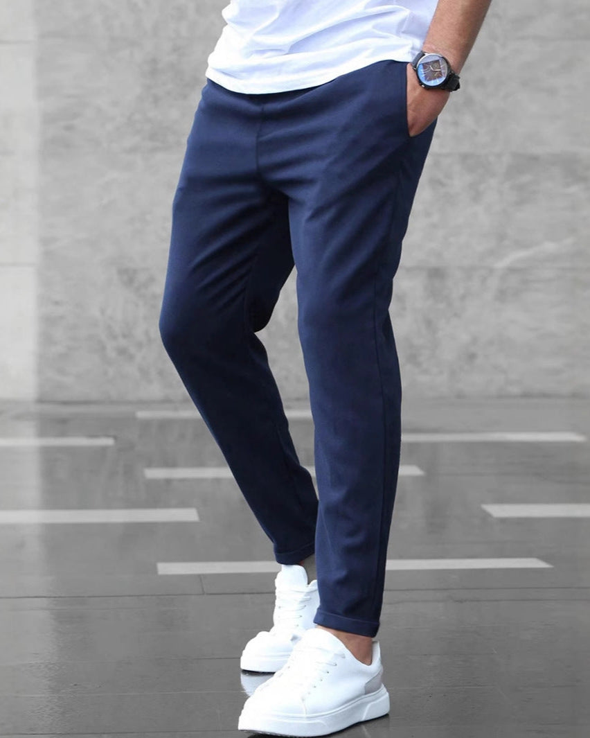 Uomo con pantaloni blu eleganti e scarpe bianche su sfondo grigio. Stile casual chic, moda maschile, abbigliamento moderno.