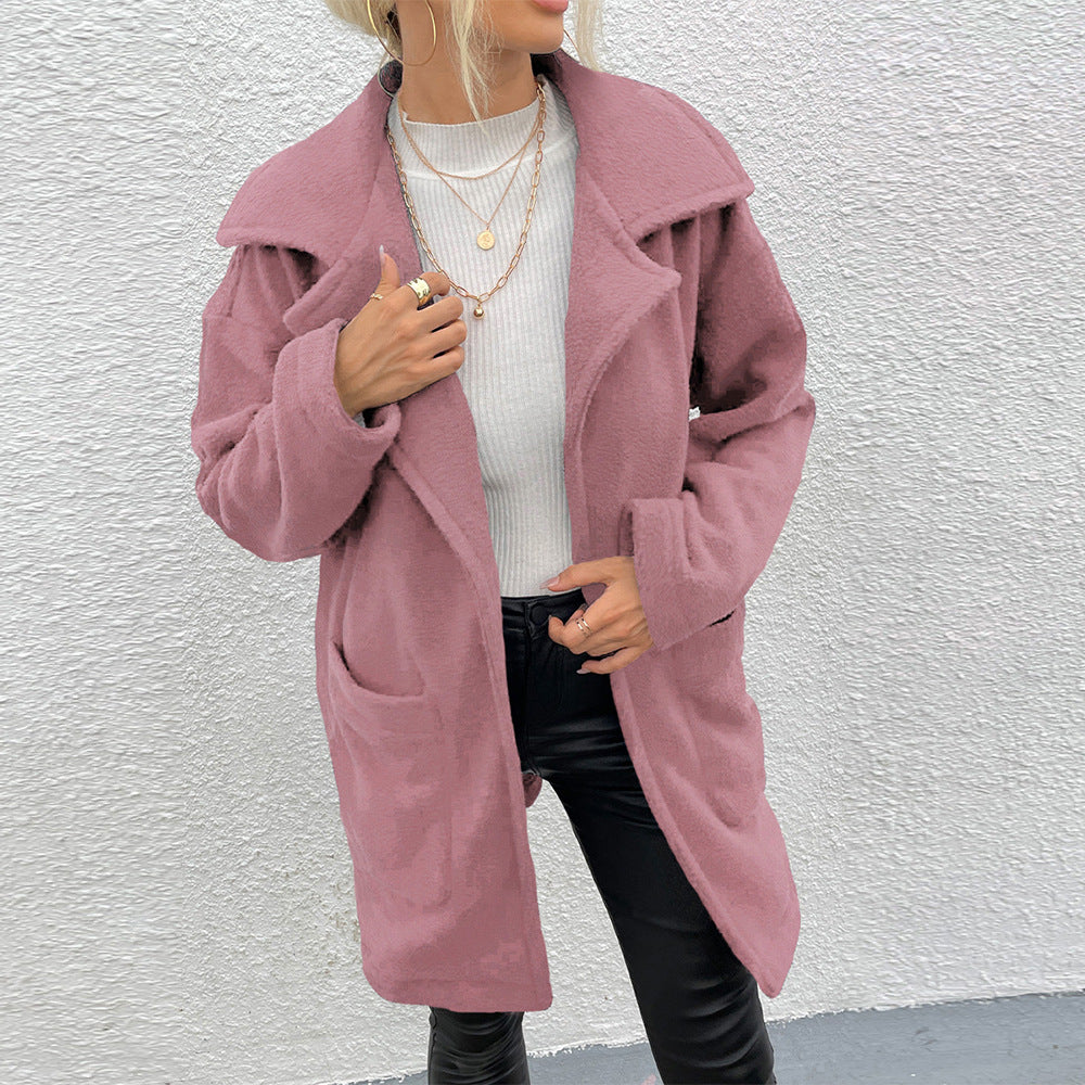 Donna con cappotto rosa in lana, maglia bianca e pantaloni neri in pelle. Moda autunnale, stile casual chic, accessori con collane dorate.