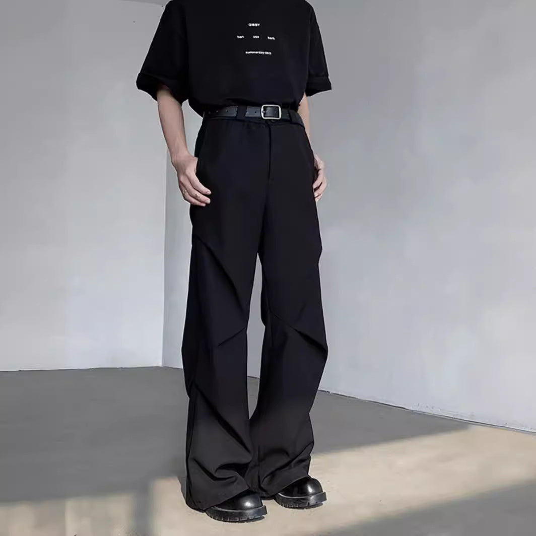 Uomo in abbigliamento nero minimalista, indossa pantaloni larghi e t-shirt, scarpe nere. Moda contemporanea, stile urbano, outfit casual.