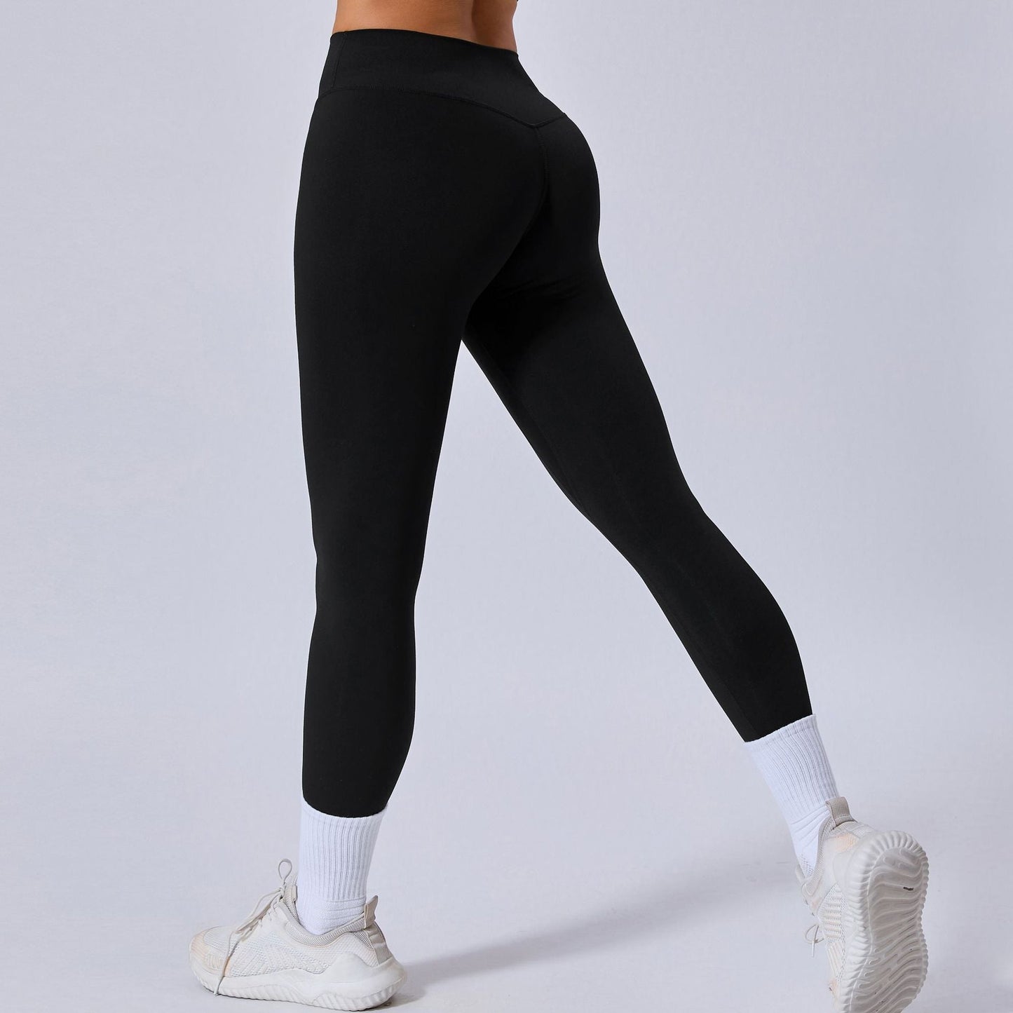 Donna in leggings neri sportivi, scarpe da ginnastica bianche e calzini alti. Abbigliamento fitness, moda attiva, comfort e stile.