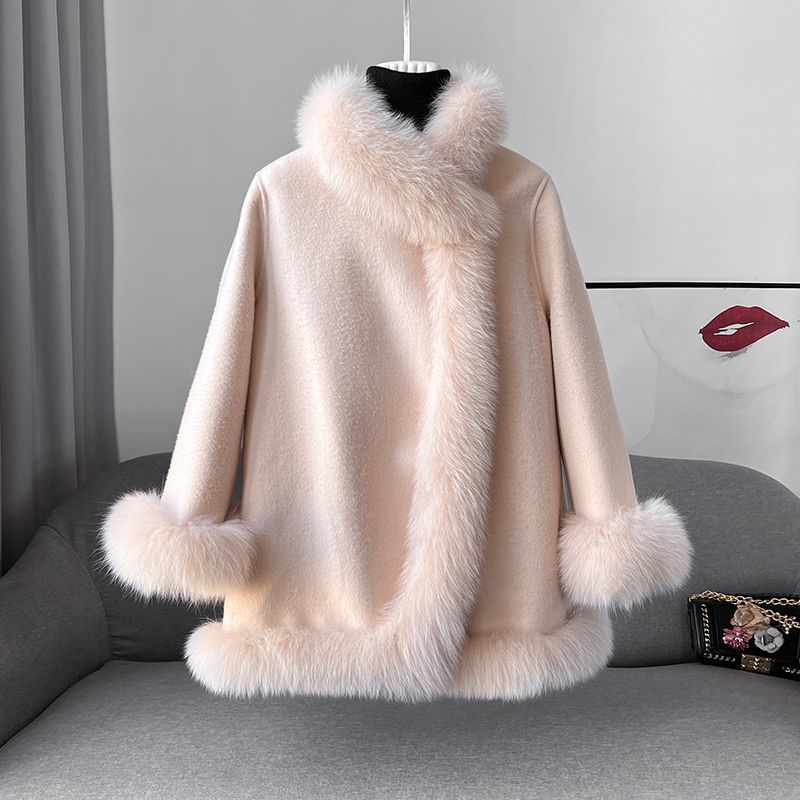 Cappotto invernale donna in lana rosa con bordo in pelliccia sintetica, elegante e caldo, su divano grigio. Moda femminile, abbigliamento autunnale.