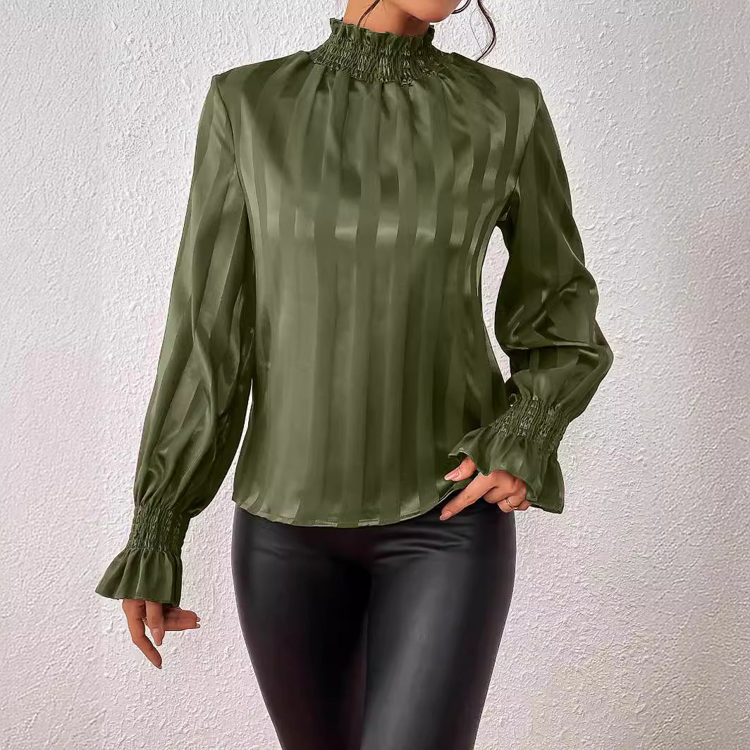 Blusa verde oliva a righe verticali con maniche lunghe e polsini arricciati, abbinata a pantaloni in pelle nera. Moda elegante e sofisticata.