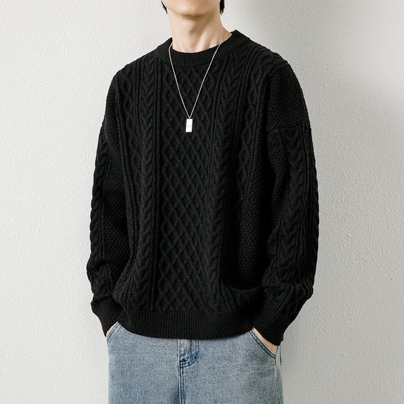 Maglione nero a trecce indossato da uomo, abbinato a jeans chiari e collana argento. Moda casual autunnale, stile elegante e moderno.