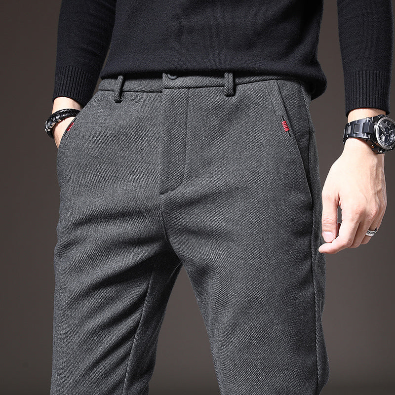 Uomo in pantaloni grigi eleganti, maglione nero, orologio al polso. Moda maschile autunno inverno, abbigliamento casual chic.