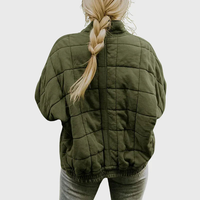 Donna con giacca trapuntata verde oliva, capelli biondi intrecciati, vista posteriore. Moda autunnale, abbigliamento casual, stile moderno.