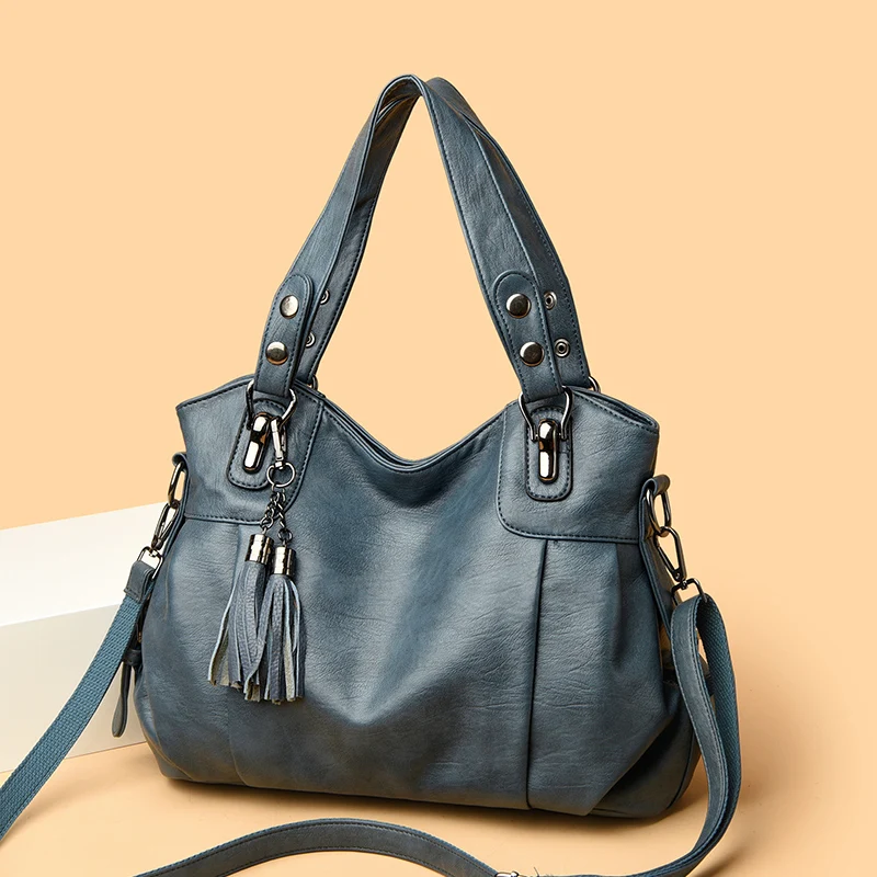 Borsa a spalla in pelle blu con dettagli metallici e nappine decorative, design elegante e moderno, perfetta per moda donna e accessori di tendenza.