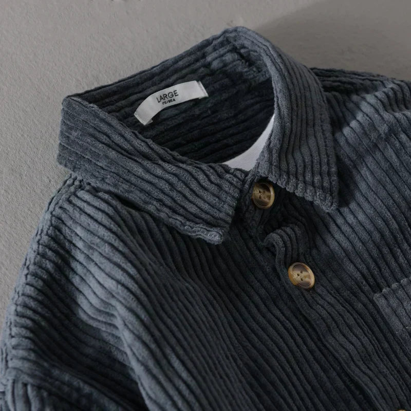 Camicia in velluto a coste grigio scuro con colletto classico e bottoni in legno, etichetta interna visibile. Moda uomo autunno inverno.