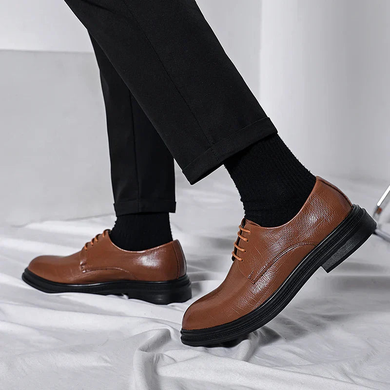 Scarpe eleganti uomo in pelle marrone, suola nera, indossate con pantaloni neri. Calzature formali, moda maschile, stile classico.