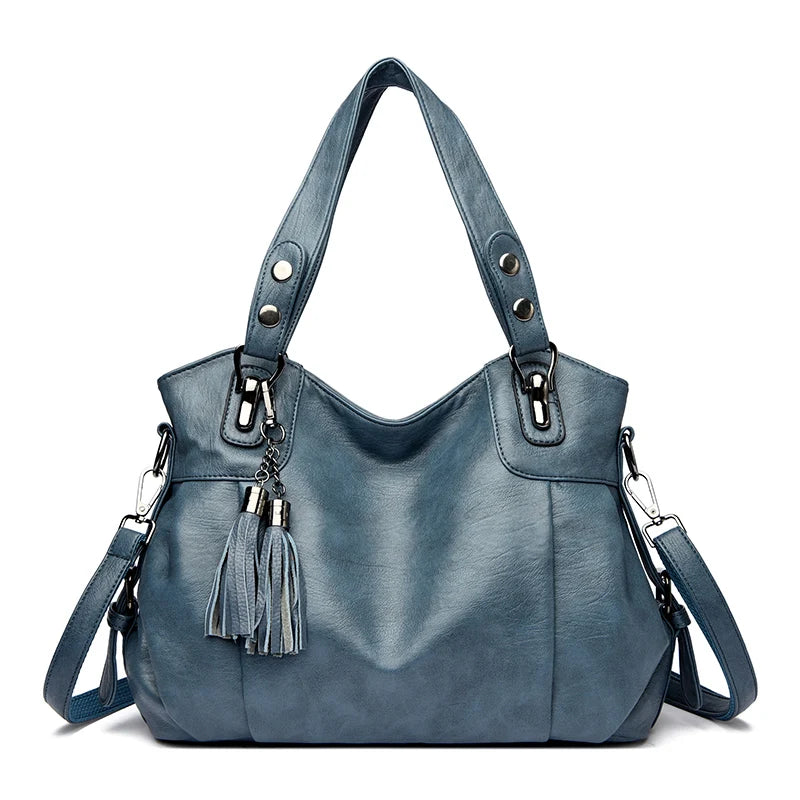 Borsa a spalla in pelle blu con nappe decorative, manici robusti e tracolla regolabile. Elegante accessorio moda donna.