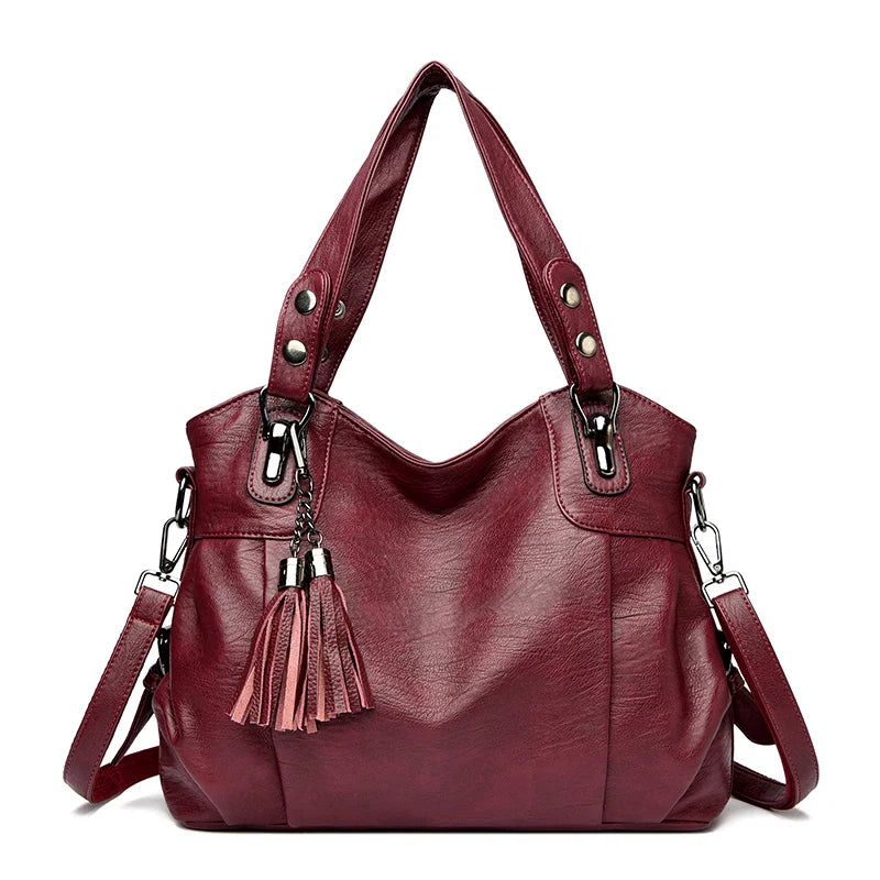 Borsa a spalla in pelle rossa con nappine decorative, manici robusti e tracolla regolabile. Elegante e spaziosa, ideale per ogni occasione.