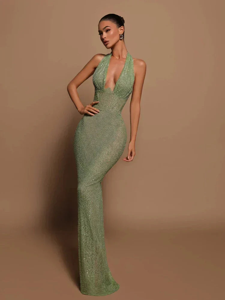 Donna in abito lungo verde scintillante, scollatura profonda, posa elegante su sfondo beige. Moda, eleganza, abito da sera glamour.