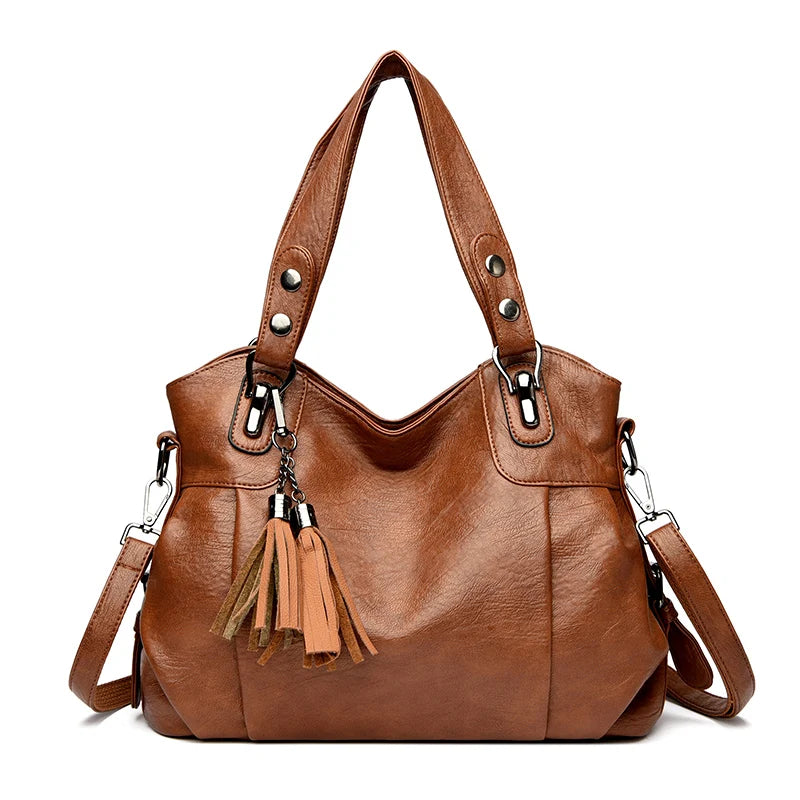 Borsa a spalla in pelle marrone con nappine decorative, manici rinforzati e tracolla regolabile. Elegante accessorio moda donna.