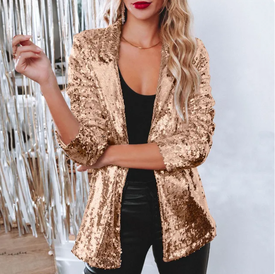 Donna con giacca di paillettes dorate, top nero e pantaloni in pelle. Moda elegante, abbigliamento da sera, stile glamour.