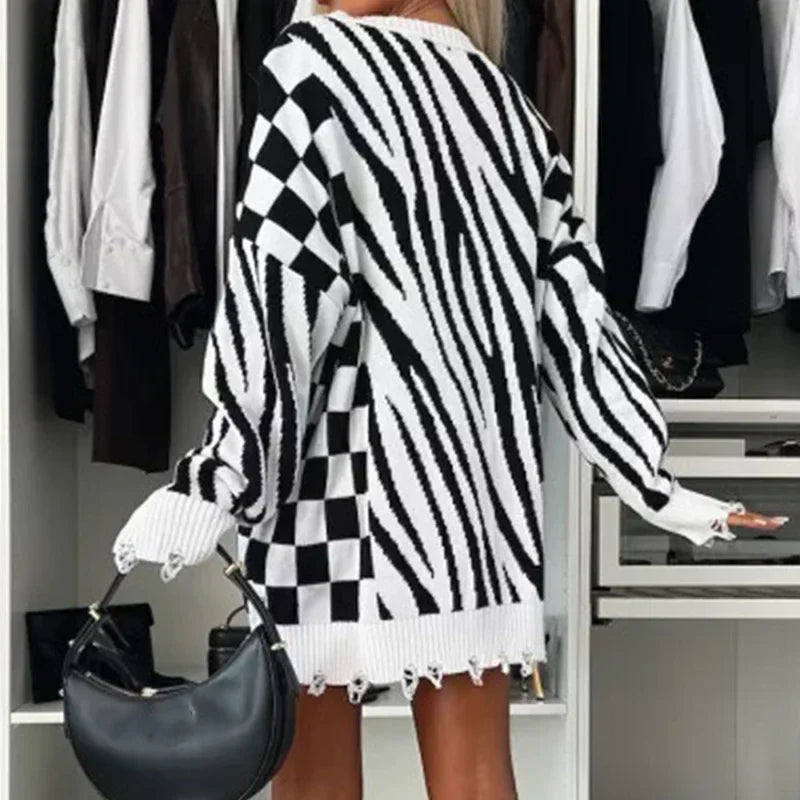 Donna con maglione oversize a righe e quadri bianco e nero, in un armadio moderno. Moda autunno, stile casual chic, tendenze abbigliamento 2023.