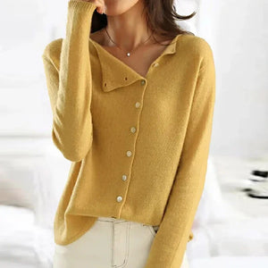 Donna con maglione giallo a maniche lunghe e bottoni, in posa casual in una stanza luminosa. Moda autunnale, abbigliamento femminile elegante.