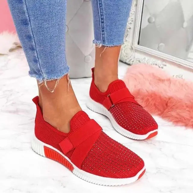 Scarpe da ginnastica rosse da donna con strass, suola bianca, indossate con jeans strappati. Design moderno e casual, perfette per moda urbana.