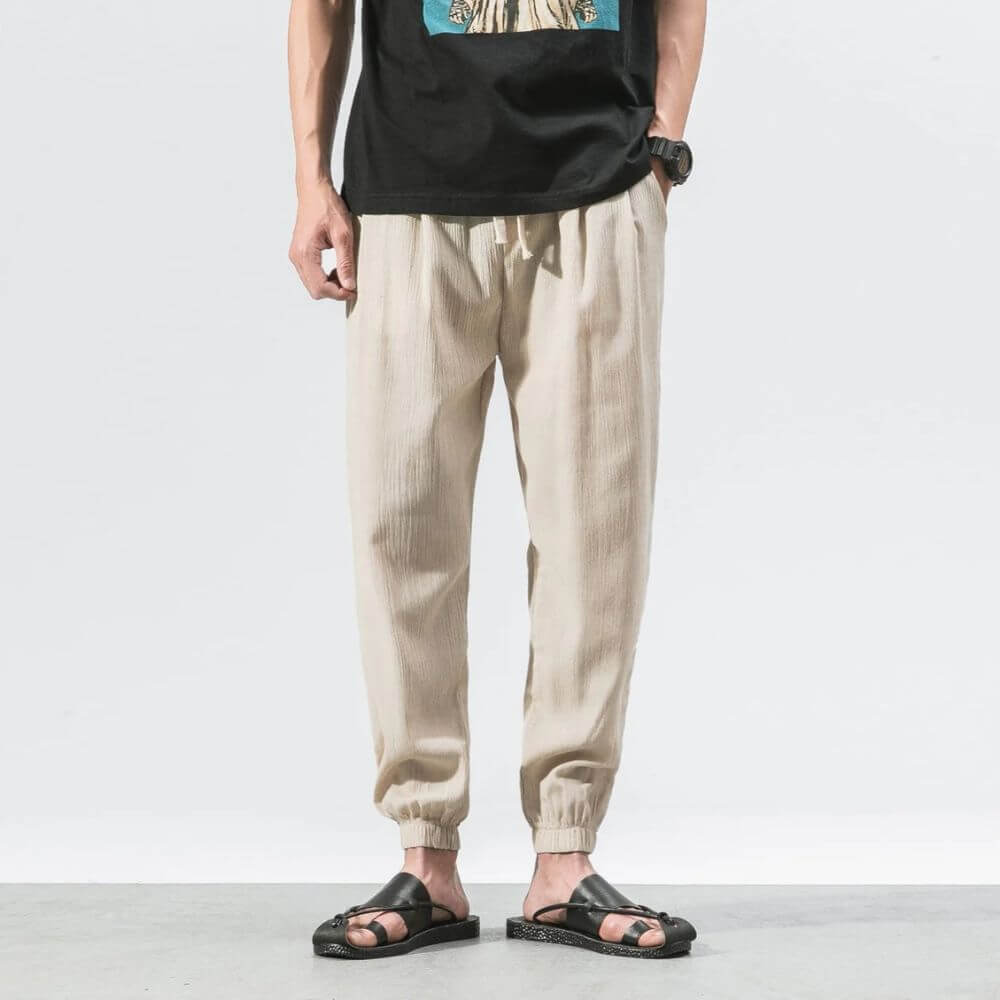 Uomo in pantaloni beige casual, t-shirt nera, sandali neri. Moda estiva maschile, abbigliamento comodo, stile urbano.