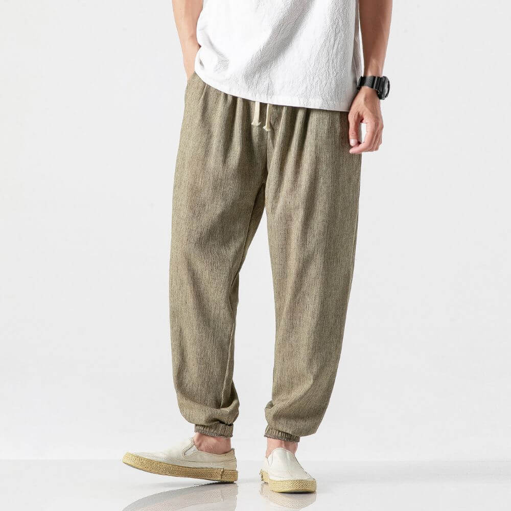 Pantaloni larghi in lino beige, indossati con t-shirt bianca e scarpe casual. Stile casual uomo, moda estiva, comfort e leggerezza.