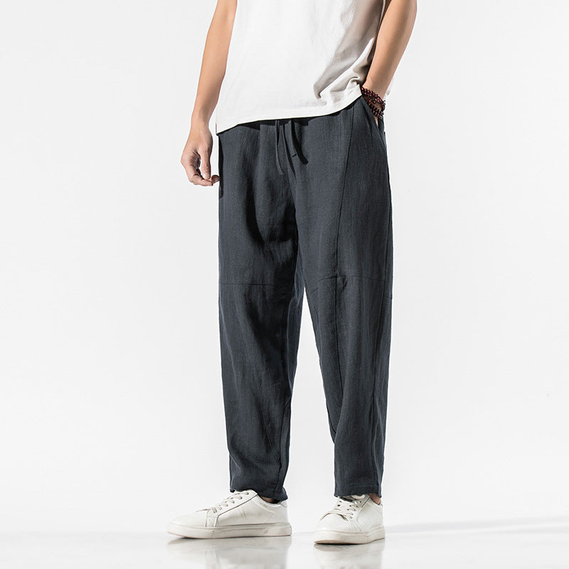 Uomo in pantaloni larghi neri e maglietta bianca, indossa scarpe da ginnastica bianche. Stile casual, moda maschile, abbigliamento comodo.