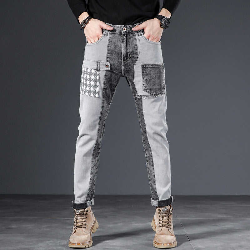 Jeans uomo grigi con design patchwork, tasche multiple e dettagli geometrici, indossati con stivali marroni. Moda casual maschile.