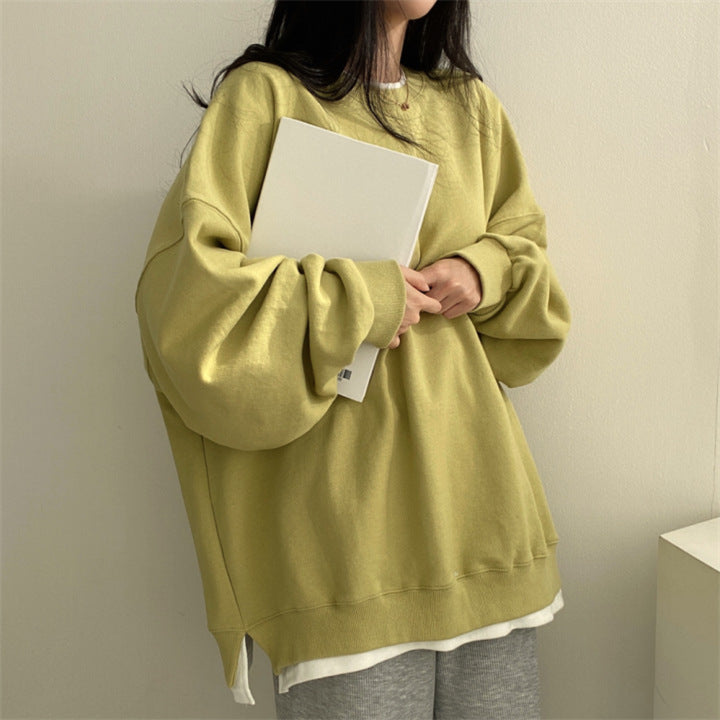 Donna con felpa oversize gialla, tiene un libro bianco. Moda casual, abbigliamento comodo, stile rilassato. Sfondo neutro, atmosfera minimalista.