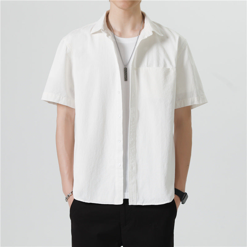 Camicia bianca uomo a maniche corte, stile casual, abbinata a t-shirt bianca e pantaloni neri. Look estivo elegante e moderno.