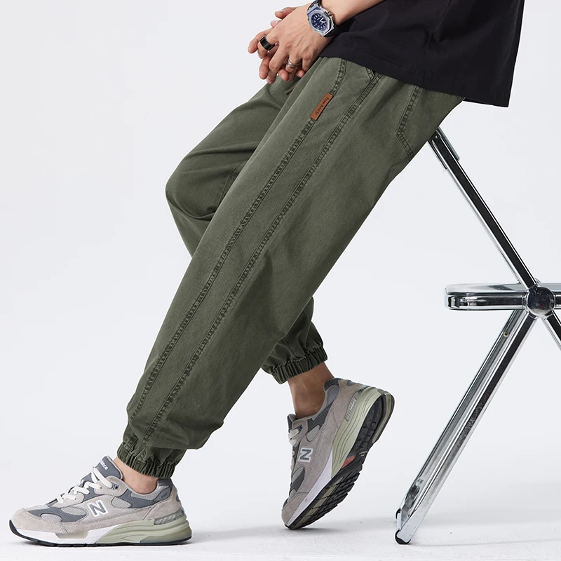 Pantaloni cargo verdi da uomo, stile casual, abbinati a scarpe sportive grigie, seduto su una sedia. Moda streetwear, comfort quotidiano.