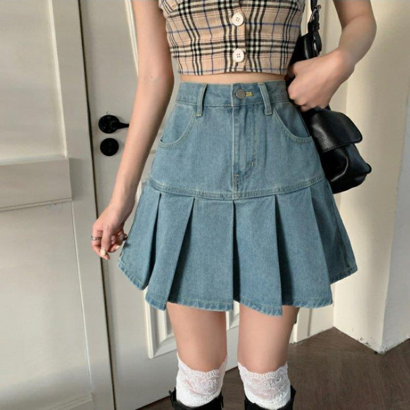 Donna con top a quadri e gonna di jeans a pieghe, borsa nera, calze bianche e stivali. Moda casual femminile, outfit estivo trendy.