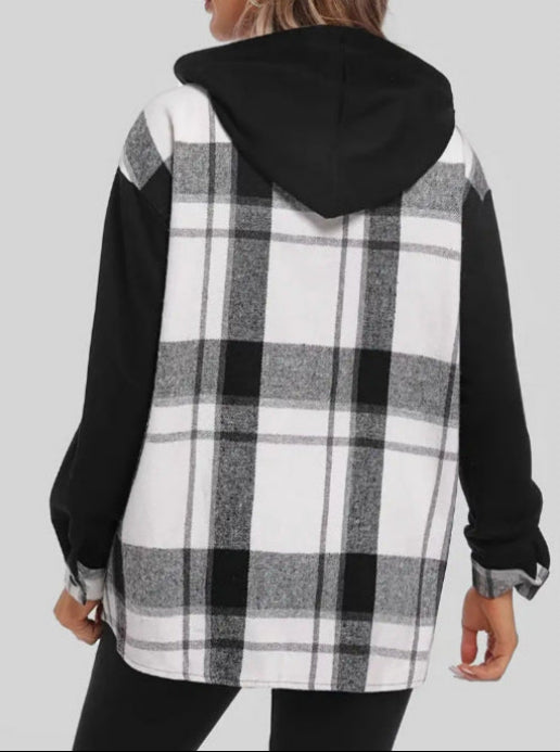 Giacca a quadri bianco e nero con cappuccio, maniche lunghe nere, indossata da una persona di spalle. Moda casual autunno inverno.