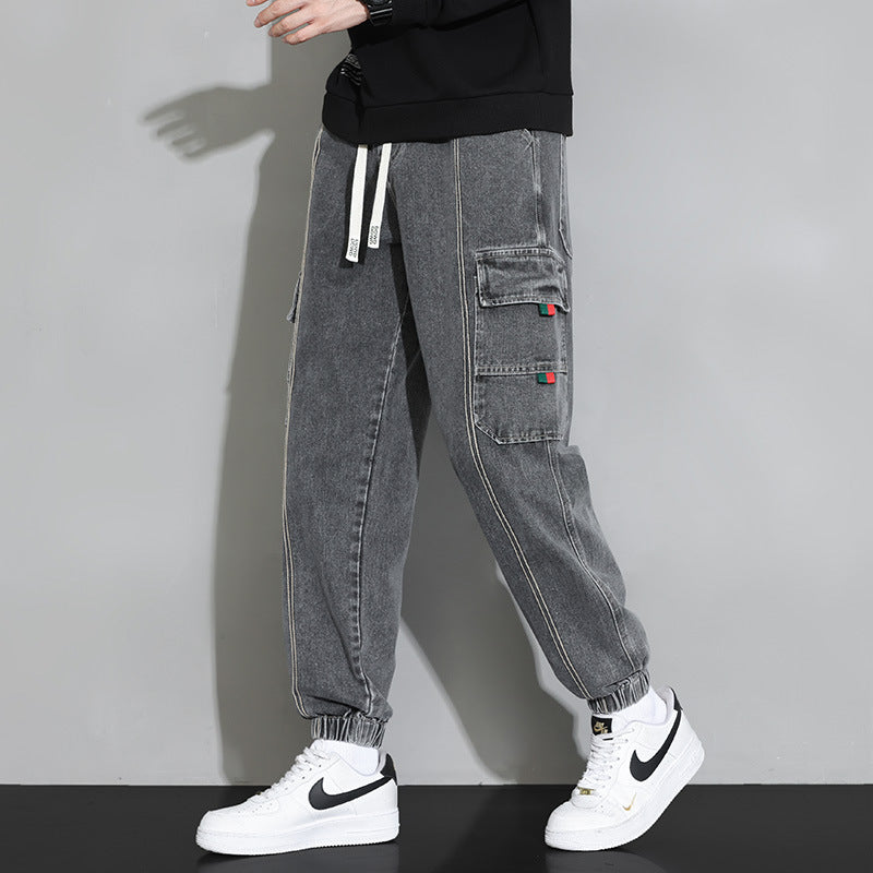 Pantaloni cargo grigi da uomo con tasche laterali, indossati con sneakers bianche Nike. Stile casual, moda streetwear, abbigliamento urbano.