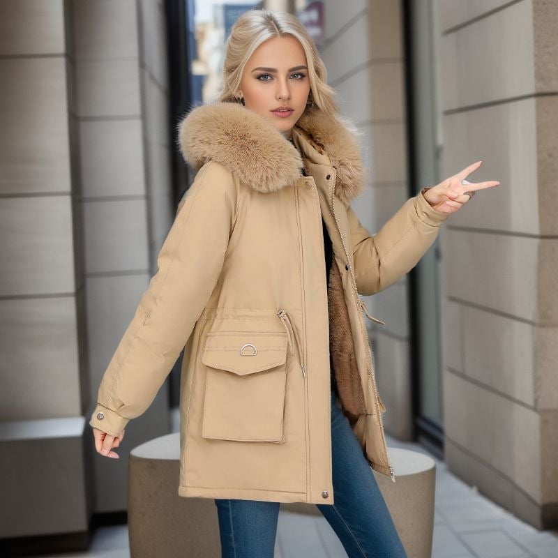 Giovane donna in cappotto beige con cappuccio in pelliccia, posa in strada urbana. Moda invernale, abbigliamento elegante, tendenze 2023.