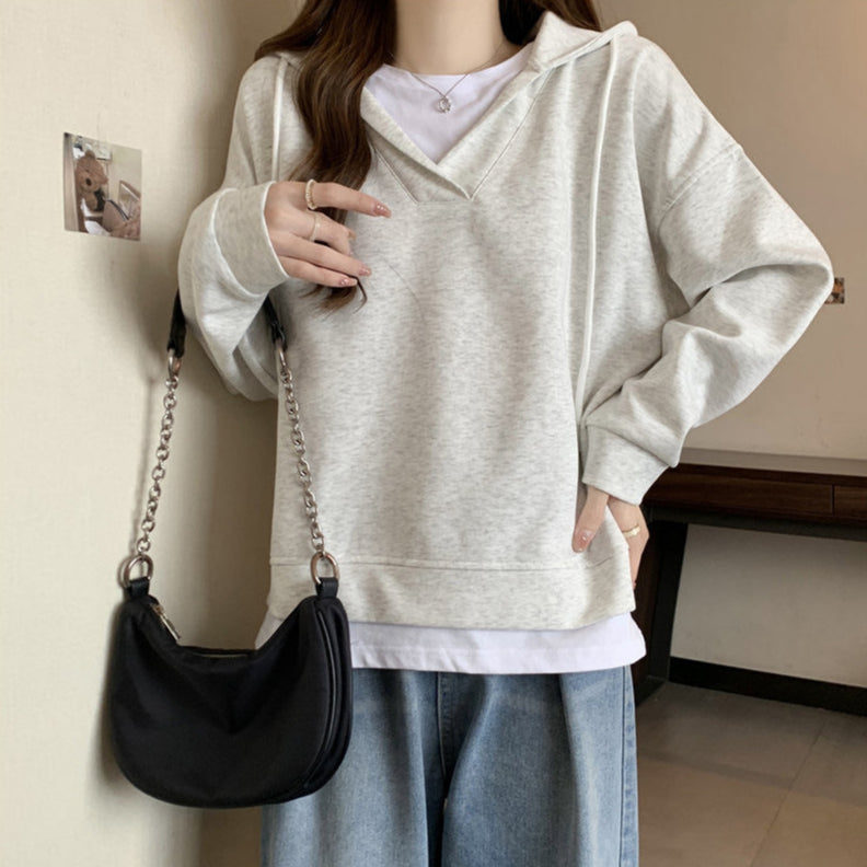 Donna con felpa grigia oversize, jeans larghi e borsa a tracolla nera. Moda casual autunnale, abbigliamento comodo e trendy per il tempo libero.