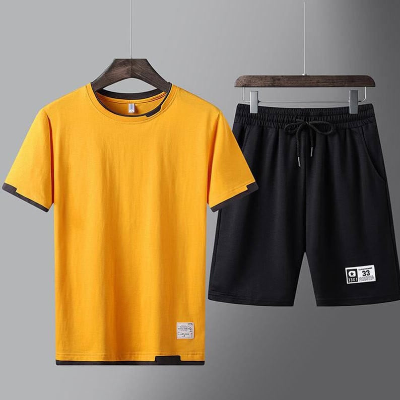 Completo sportivo estivo uomo: maglietta gialla e pantaloncini neri. Abbigliamento casual, moda estiva, outfit comodo e moderno.