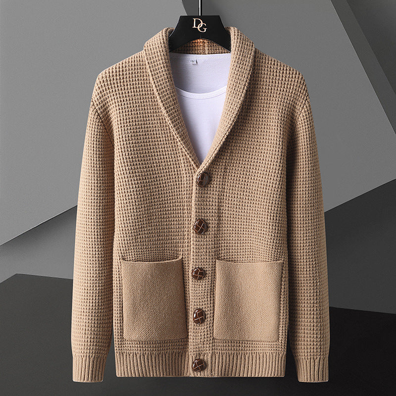 Cardigan beige in maglia a coste con bottoni in legno, tasche frontali e colletto a scialle, appeso su gruccia nera. Moda uomo autunno inverno.