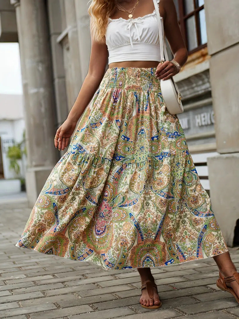 Donna con top bianco e gonna lunga a fantasia paisley colorata, borsa a tracolla bianca, sandali marroni, in strada urbana. Moda estiva casual.