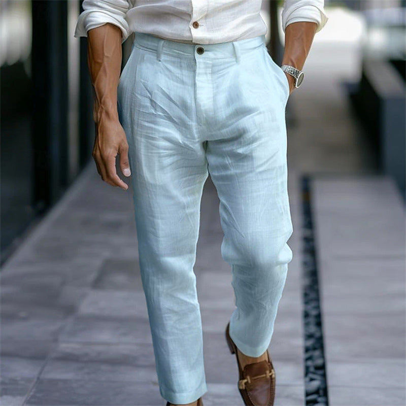 Uomo in camicia bianca e pantaloni di lino azzurri, cammina su marciapiede. Moda estiva maschile, abbigliamento casual elegante.