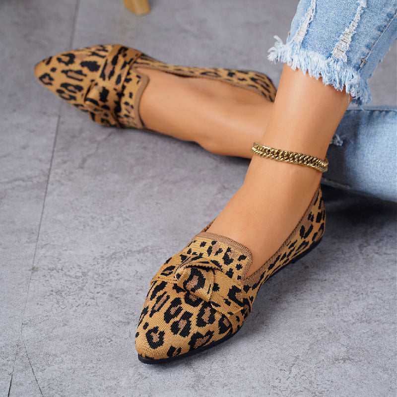 Scarpe ballerine leopardate su pavimento grigio, indossate con jeans strappati. Moda donna, calzature eleganti, stile casual chic.