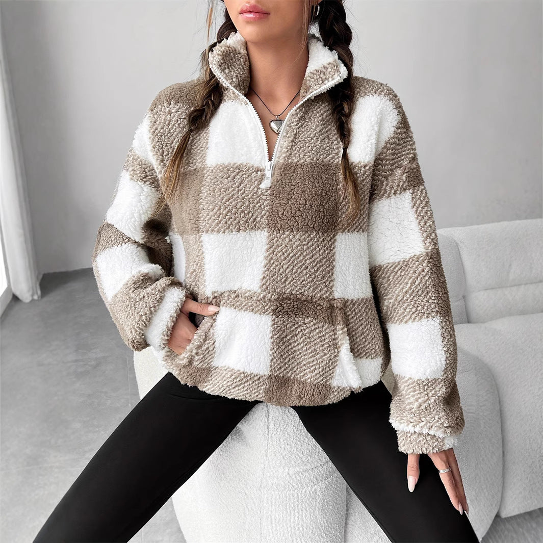 Donna con maglione a quadri beige e bianco, seduta su sedia moderna. Moda autunno inverno, abbigliamento casual, stile contemporaneo.