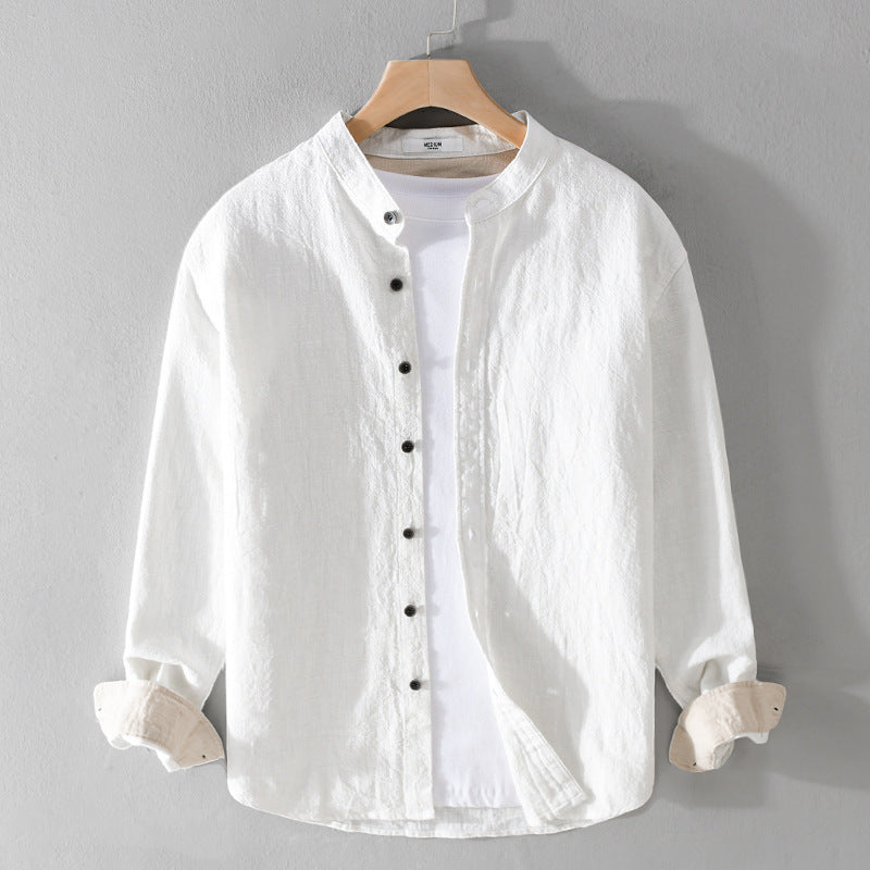 Camicia bianca in lino da uomo con colletto alla coreana, bottoni neri, maniche lunghe, appesa su gruccia. Stile casual elegante, moda maschile.