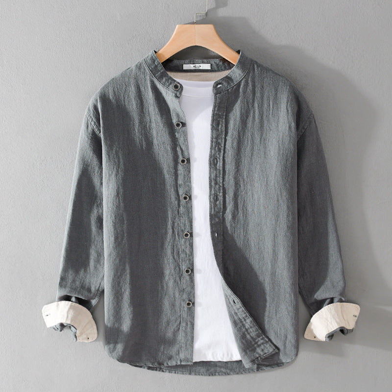 Camicia grigia in lino con colletto alla coreana, maniche lunghe, bottoni frontali, appesa su gruccia. Stile casual elegante per uomo.