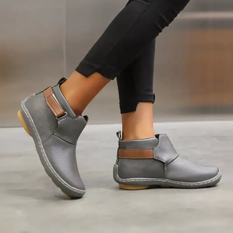 Scarpe donna invernali grigie, stivaletti casual con suola in gomma antiscivolo e cinturino marrone, indossati con pantaloni neri.
