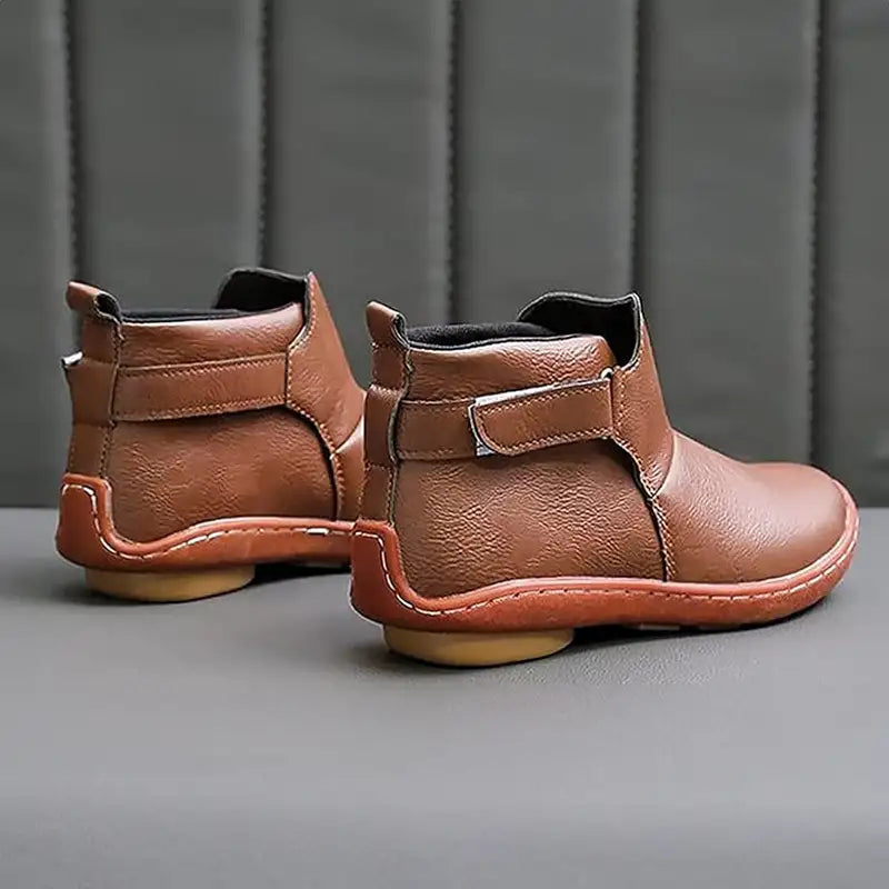Stivaletti in pelle marrone con suola in gomma, design moderno e chiusura a strappo, su sfondo grigio. Calzature eleganti e comode per uomo.